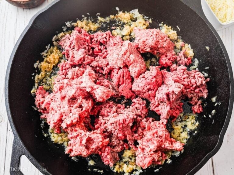 Ground beef and sausage browning in skillet with onions and garlic.
