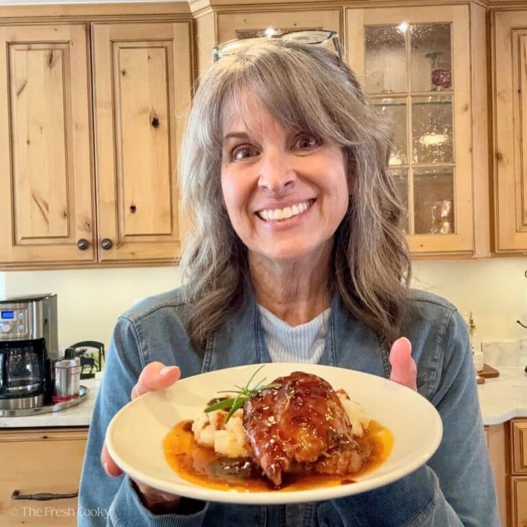 Kathleen holding plate with balsamic chicken on top of mashed potatoes.