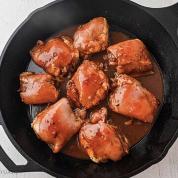 Marinated chicken thighs in a cast iron skillet to cook.