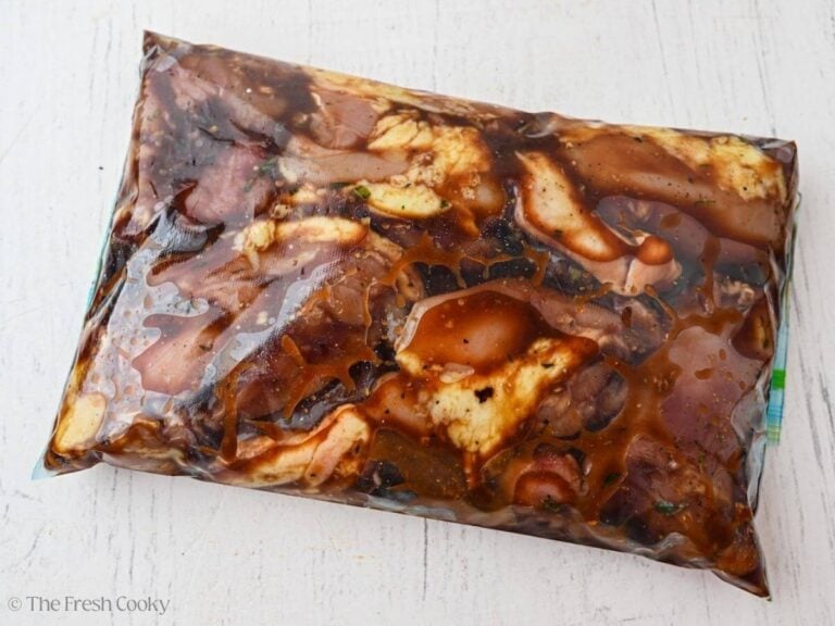 Chicken thighs marinating in balsamic marinade in a bag.