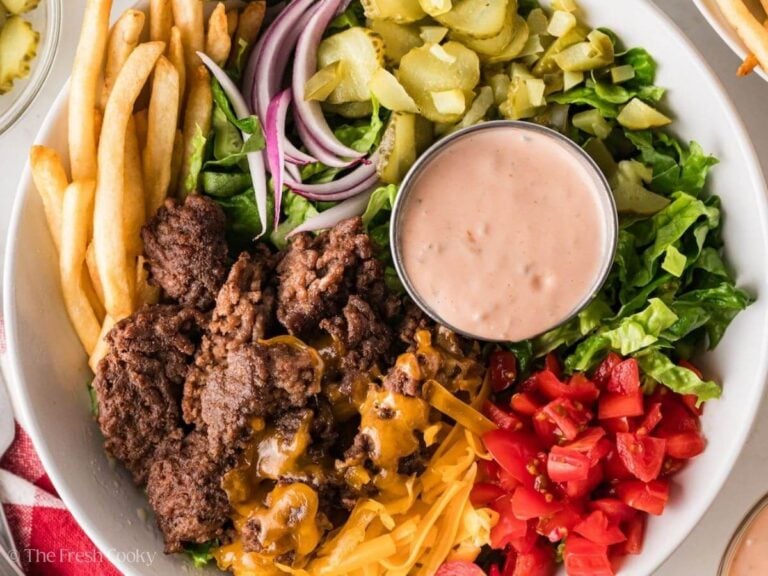 Overhead shot of a burger bowl with all the components and a ramekin of sauce.