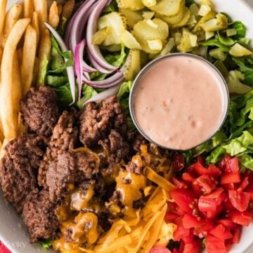 Overhead shot of a finished burger bowl with all the components and some sauce.
