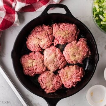 Hamburger patties in a skillet to sear.