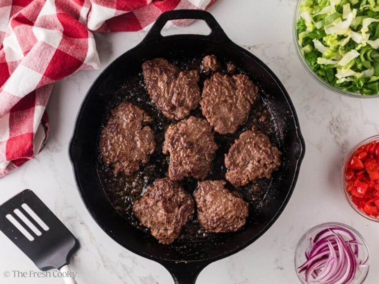 Seared hamburger patties in a cast iron skillet.
