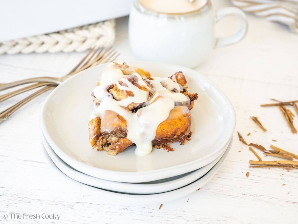 Cinnamon roll casserole serving on a plate drizzled with frosting.