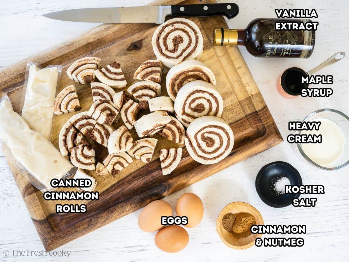 Labeled ingredients for canned cinnamon roll casserole, L-R, ccanned organic cinnamon rolls, vanilla extract, maple syrup, heavy cream, kosher salt, cinnamon and nutmeg, eggs and frosting from canned rolls.