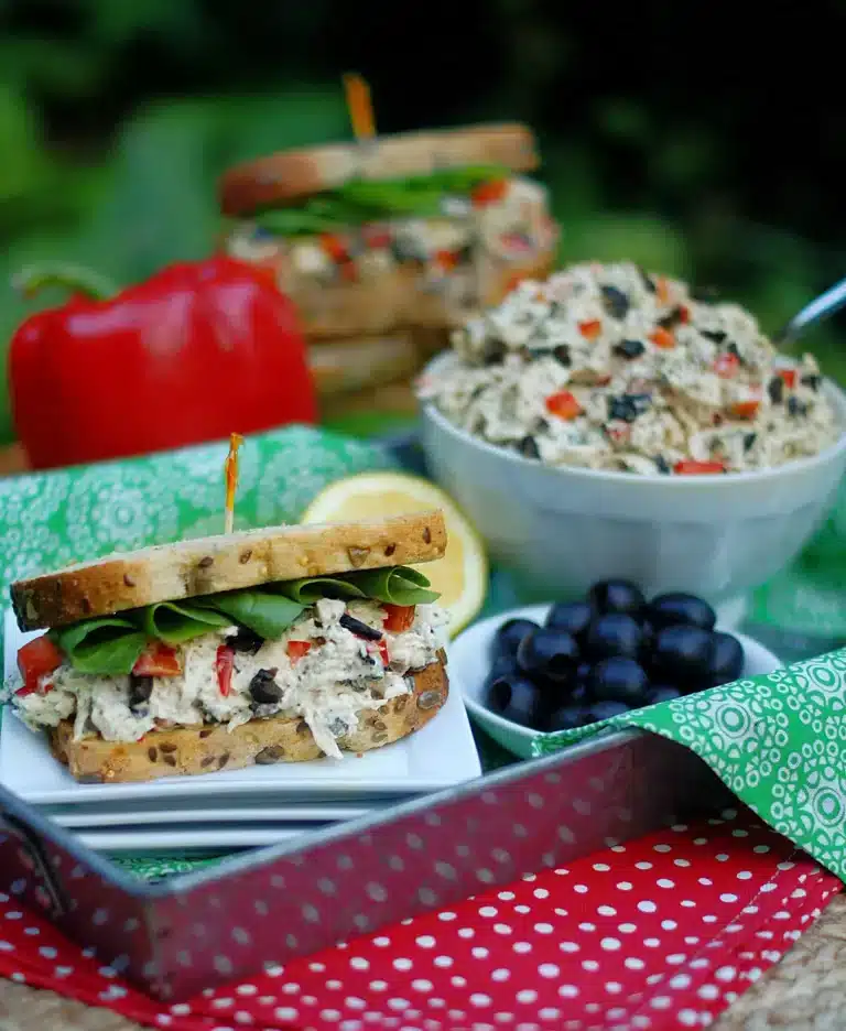 Chicken salad in a bowl and between bread as a sandwich.
