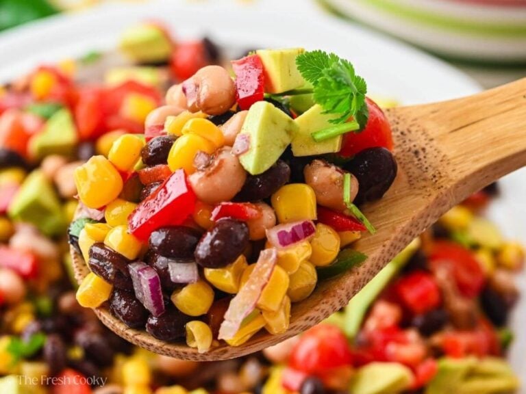 Wooden spoon scooping up some cowboy caviar from a bowl.