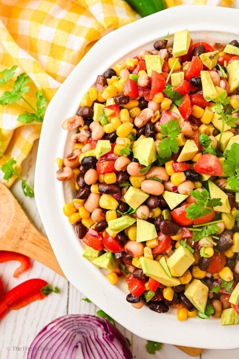 Large bowl of cowboy caviar on a table next to a yellow linen.