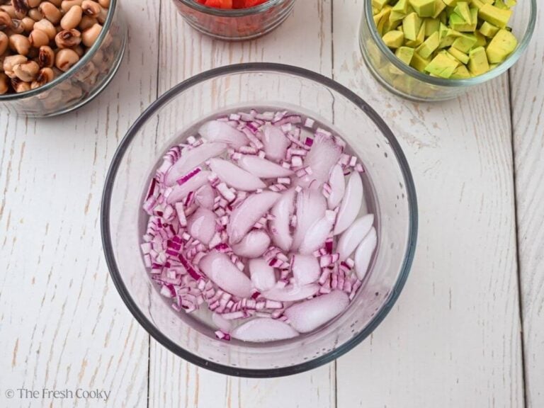 Diced red onion in a bowl with water and ice.
