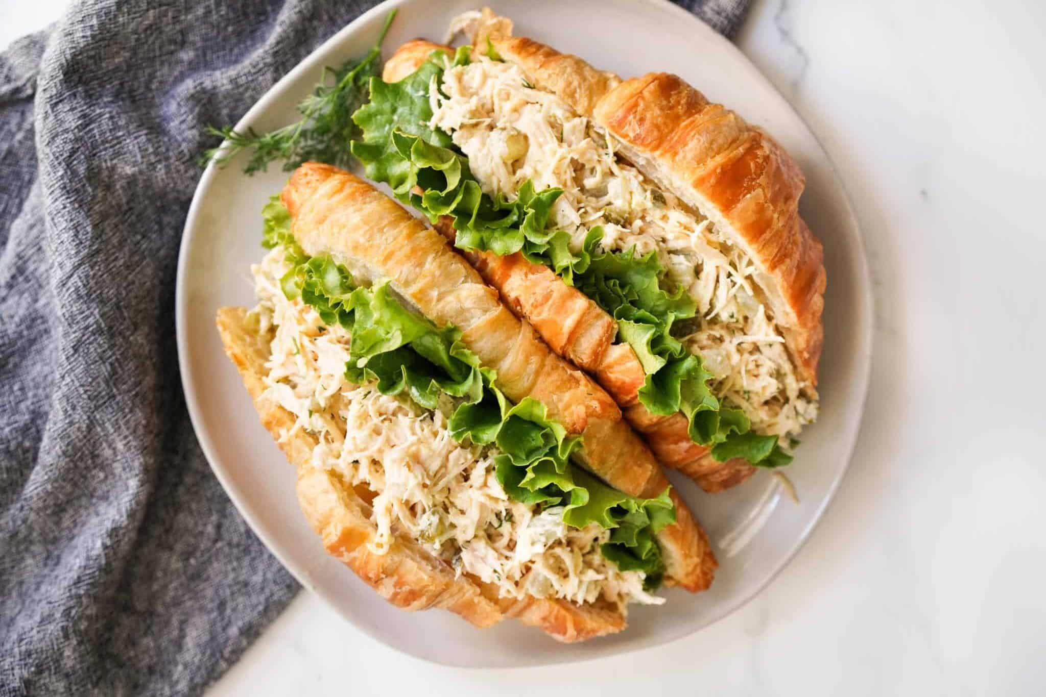 Dill pickle chicken salad in fluffy croissants with green leaf lettuce.