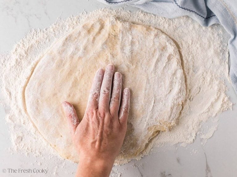 Hand pressing the donut dough down into a flat circle.