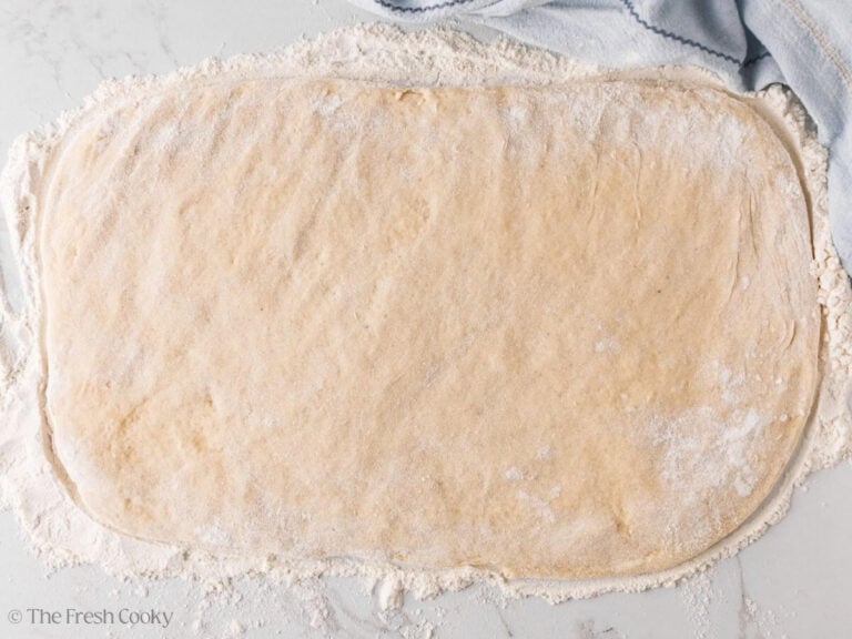 Donut dough pressed down into a large rectangle.