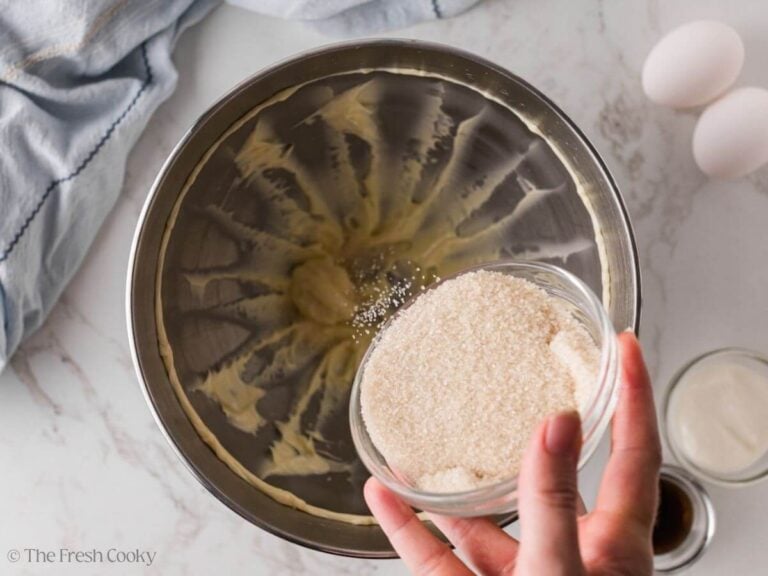 Sugar being added to the creamed butter in a mixing bowl.