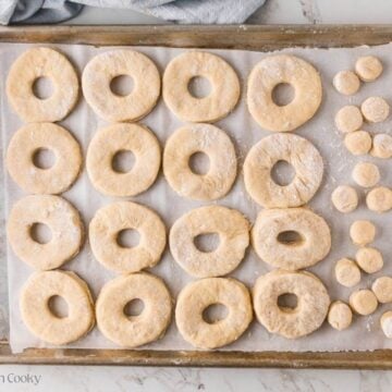 Donuts and donut holes on a sheet pan before being fried.