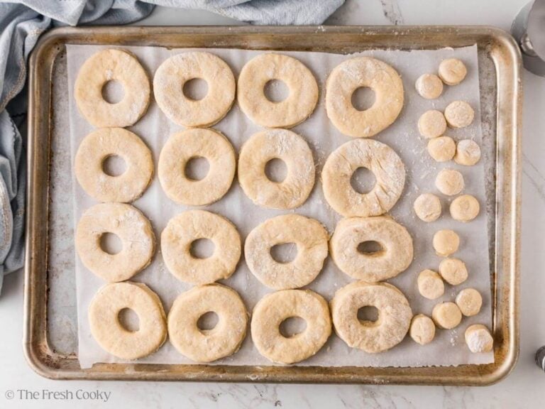 Donuts and donut holes on a sheet pan before being fried.