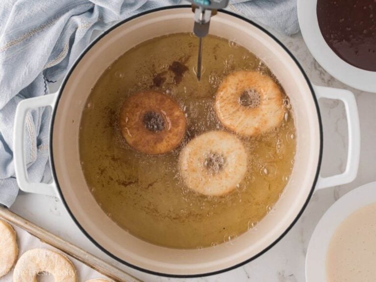 Donuts frying in hot oil in a large pot.