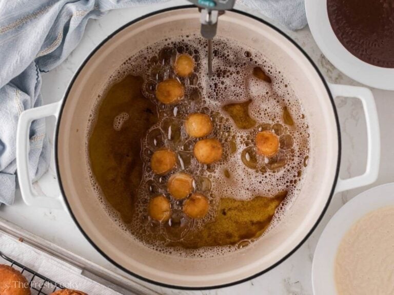Donut holes frying in a large pot of oil.