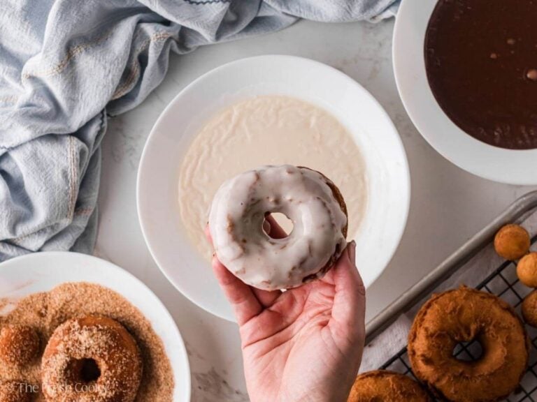 Hand holding a donut that has been dipped into glaze.