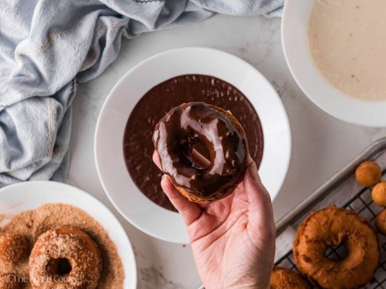 Hand holding a donut that has been dipped in chocolate glaze.