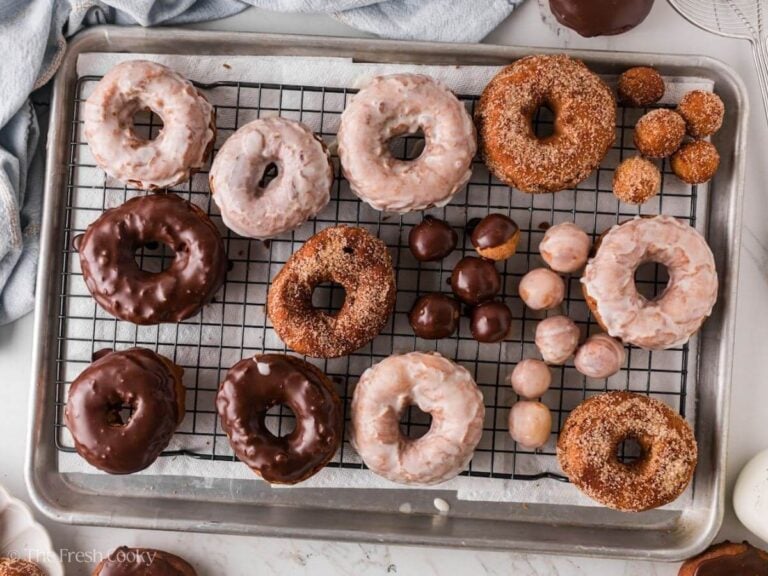 Overhead shot of glazed donuts and cinnamon sugar donuts on a wire rack on a sheet pan.