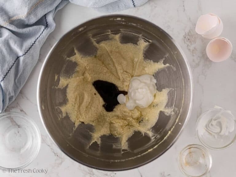Sour cream and vanilla extract added to the creamed butter and sugar in a mixing bowl.