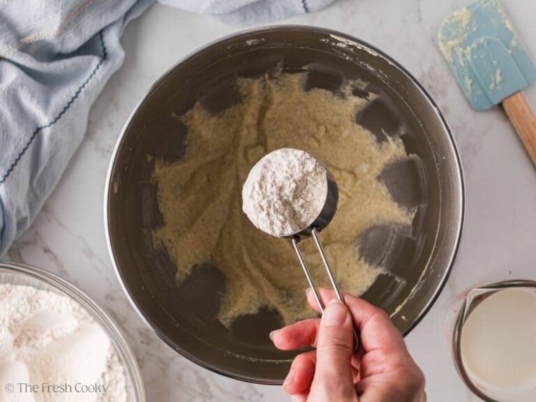 Flour being added to the wet ingredients in a mixing bowl.