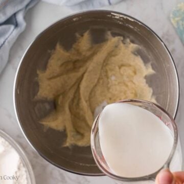 Buttermilk being added to the donut batter in a mixing bowl.