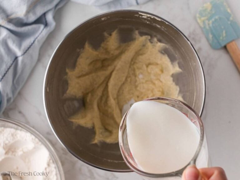 Buttermilk being added to the donut batter in a mixing bowl.