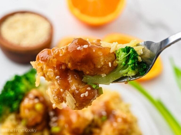 Fork with a bite of rice, broccoli and orange chicken.