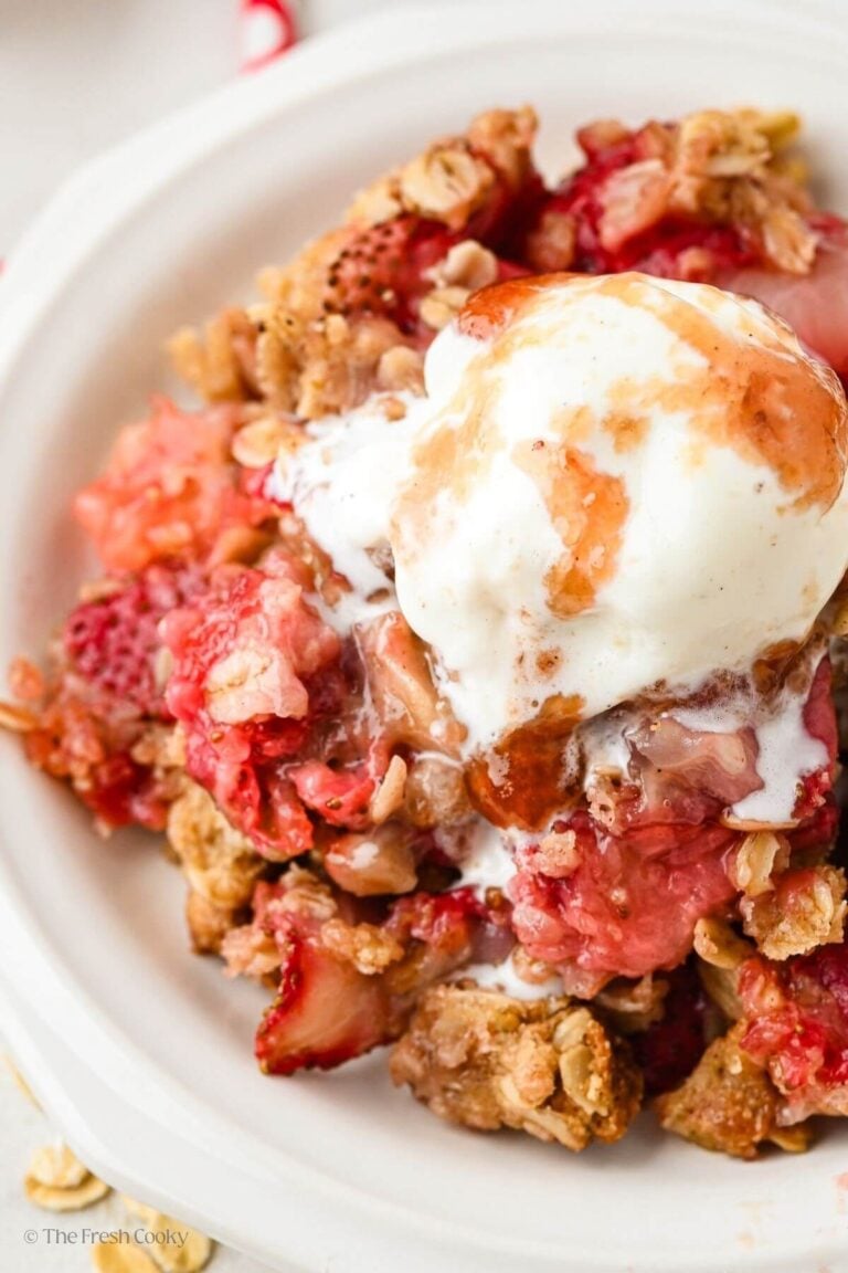 Strawberry crumble on a plate with ice cream on top.