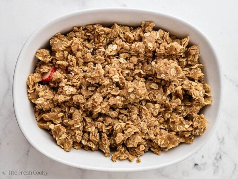 Oat crumble mixture on top of the fresh strawberries in a baking dish.