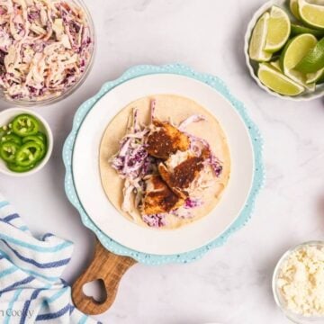Assembling tilapia fish tacos on a plate.