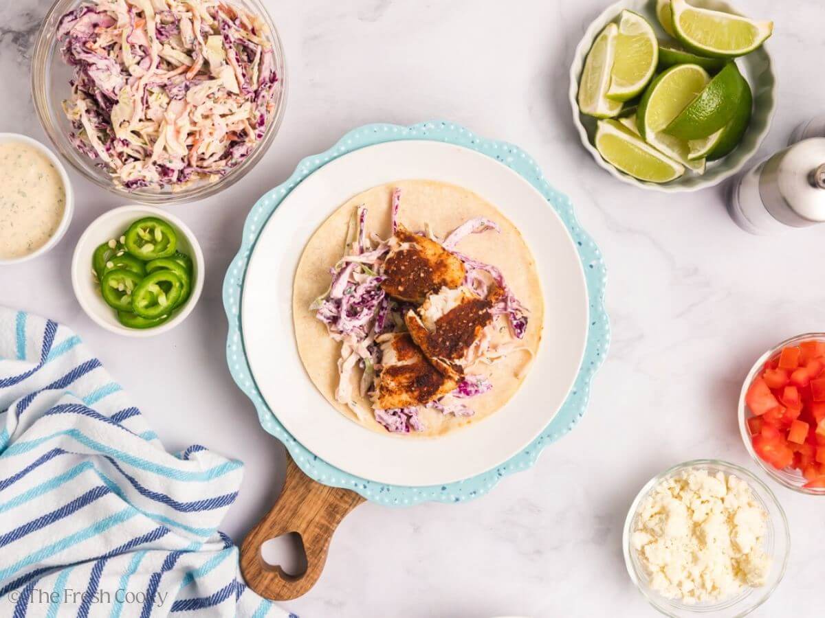 Assembling tilapia fish tacos on a plate.