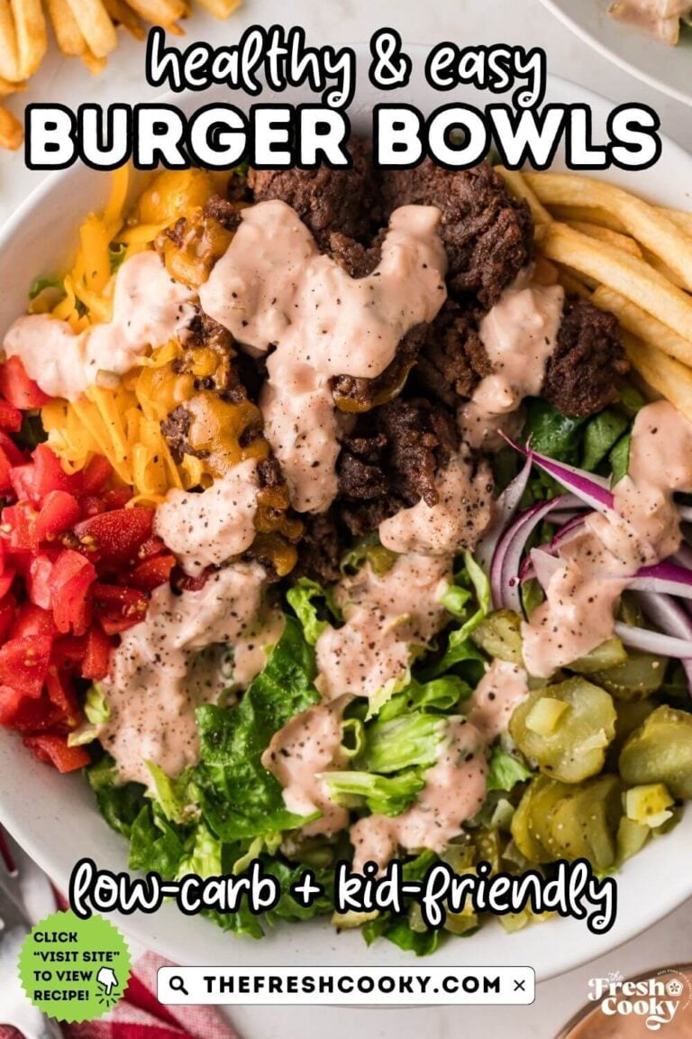 A cheeseburger bowl on lettuce, with tomatoes, pickles, red onions, cheese drizzled with sauce and some french fries on the side.