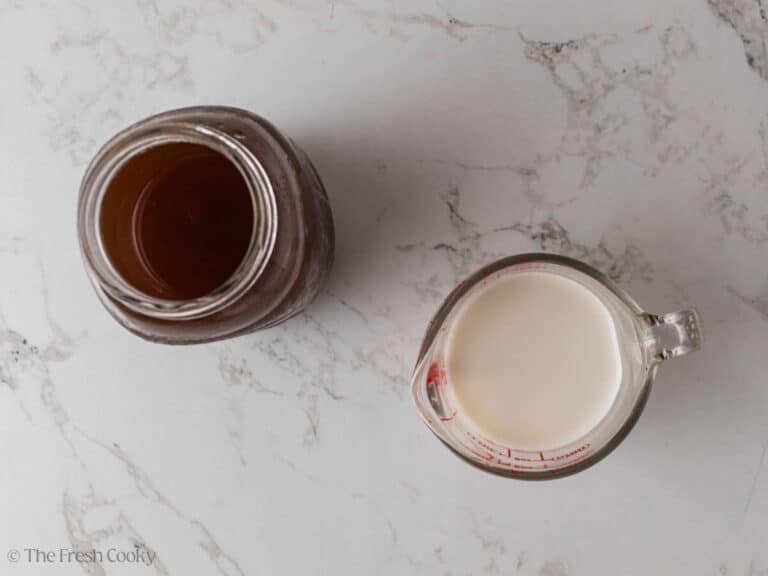 Chat tea concentrate in a jar next to milk in a measuring cup.