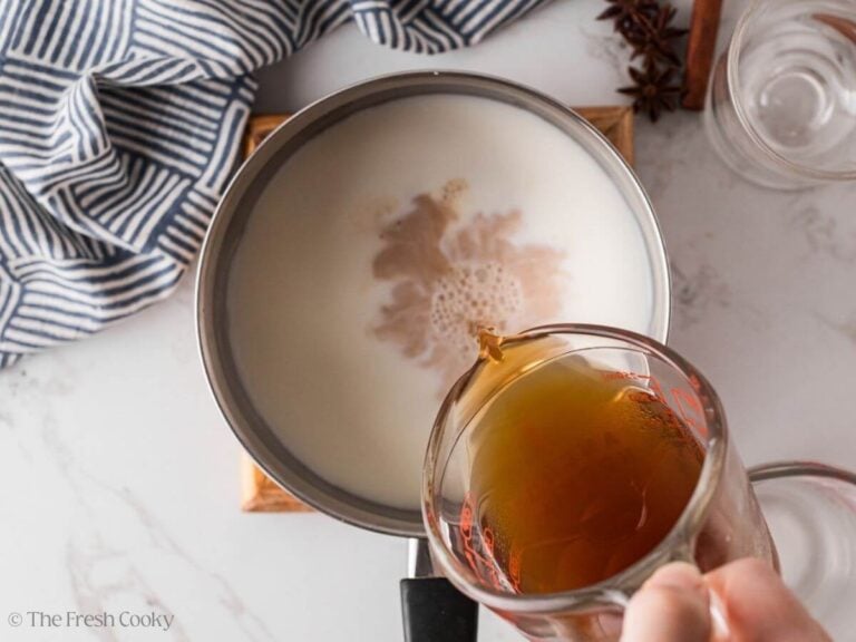Pouring chai tea concentrate into a saucepan with the milk.