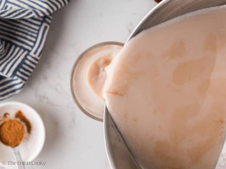 Pouring the chai tea and milk mixture into a mug.