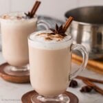 Chai tea lattes in glass mugs, both garnished with cinnamon and star anise.