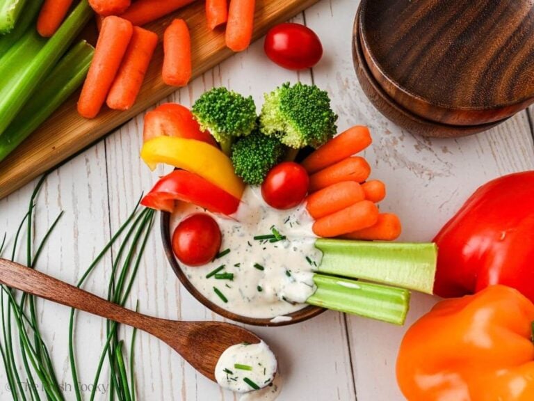 Veggie dip in a small wooden bowl with a spoon nearby, loaded with fresh, crisp vegetables for dipping.