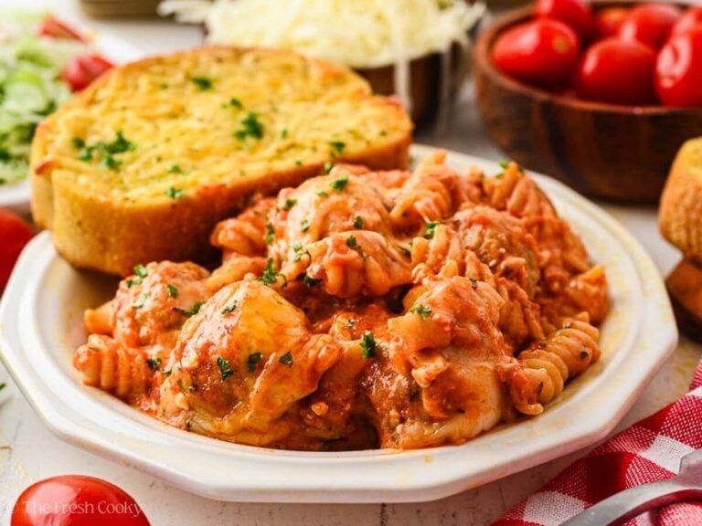 Meatball casserole served on a plate with a side of garlic bread.