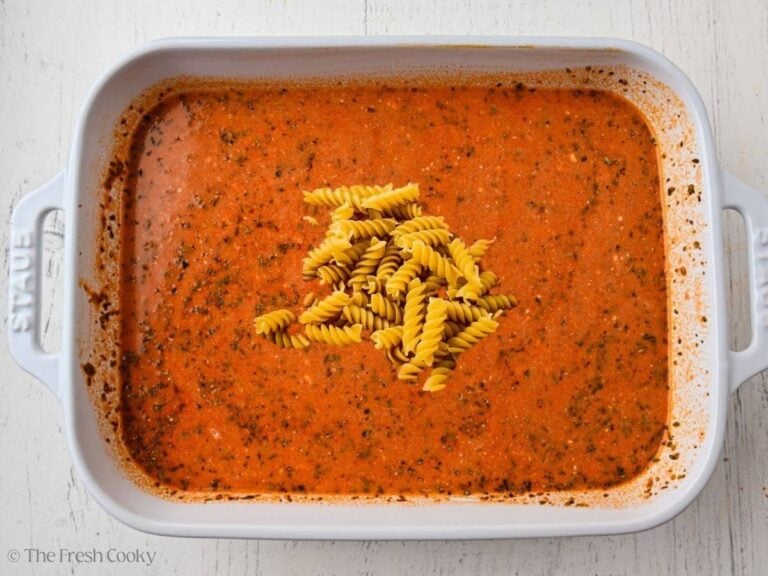 Dried pasta added to the sauce in a baking dish.