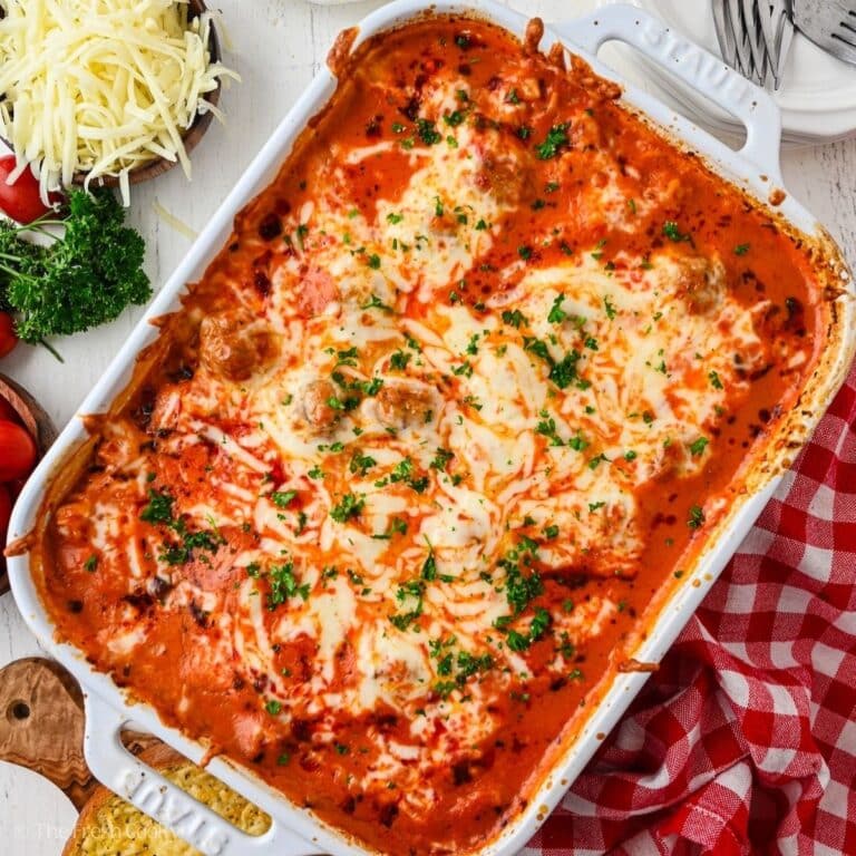 Meatball Casserole in Staub white baking dish with melty cheese on top, a dump and bake dinner.