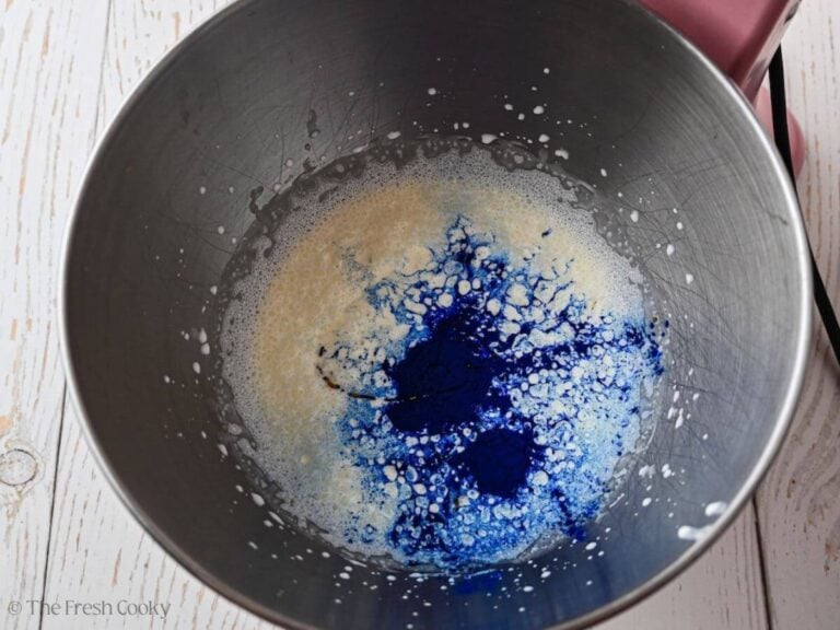 Blue spirulina added to the heavy cream in a mixing bowl.