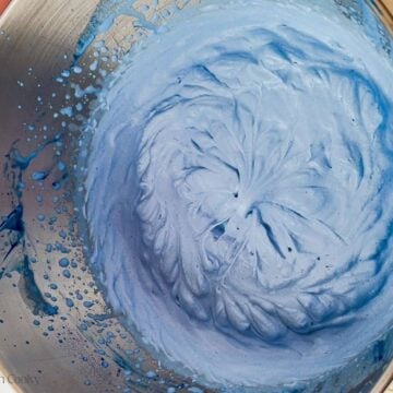 Heavy cream and blue spirulina whipped up in a mixing bowl.
