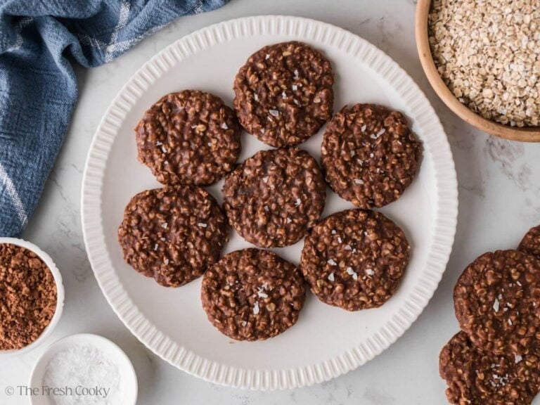 Overhead shot of no bake chocolate oat cookies on a plate next to a bowl of oats.