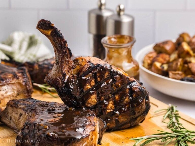 Side view of a bone-in grilled pork chop leaning on another pork chop.