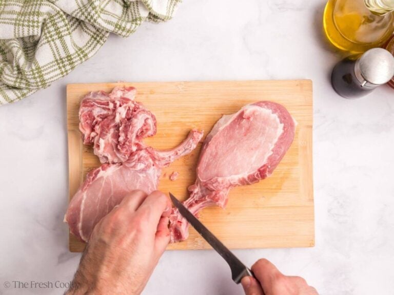 Frenching a pork chop, hands with a knife, scraping the bone clean.