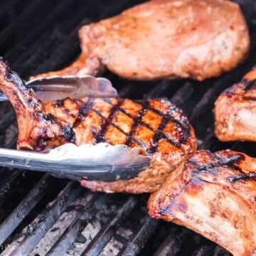 Grilled pork chops with char lines being flipped.