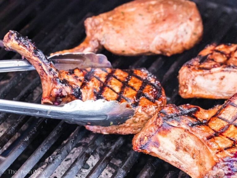 Grilled pork chops with char lines being flipped.